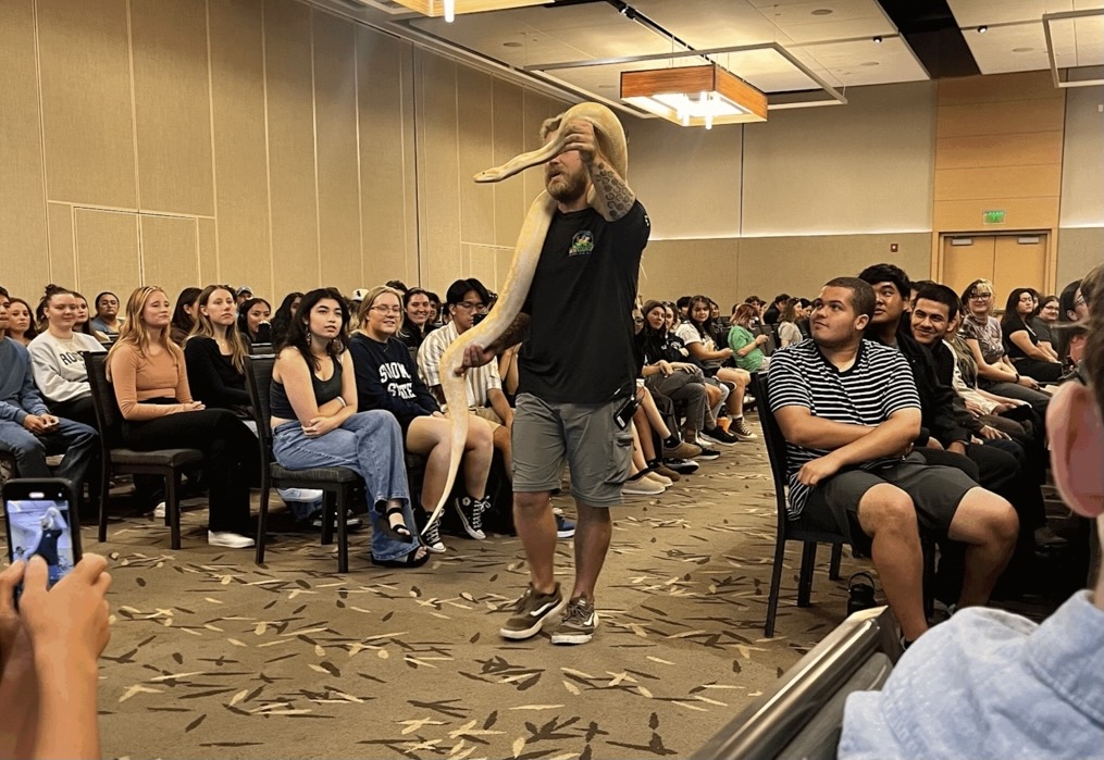 Attendees watch as presenter Daniel More holds a live python 