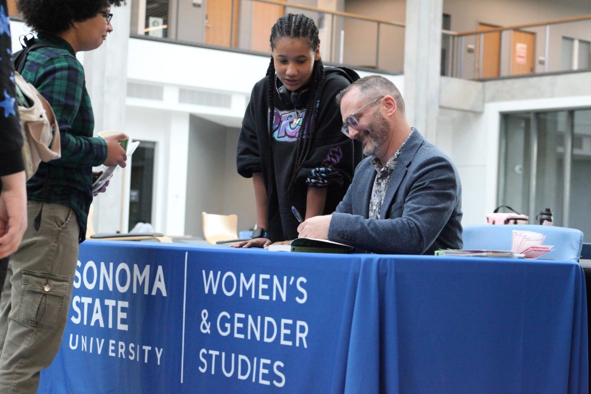 Don Romesburg signs books for attendees at his book launch in Stevenson Hall.